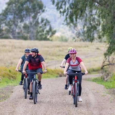 Friends riding e-bikes along a country rail trail